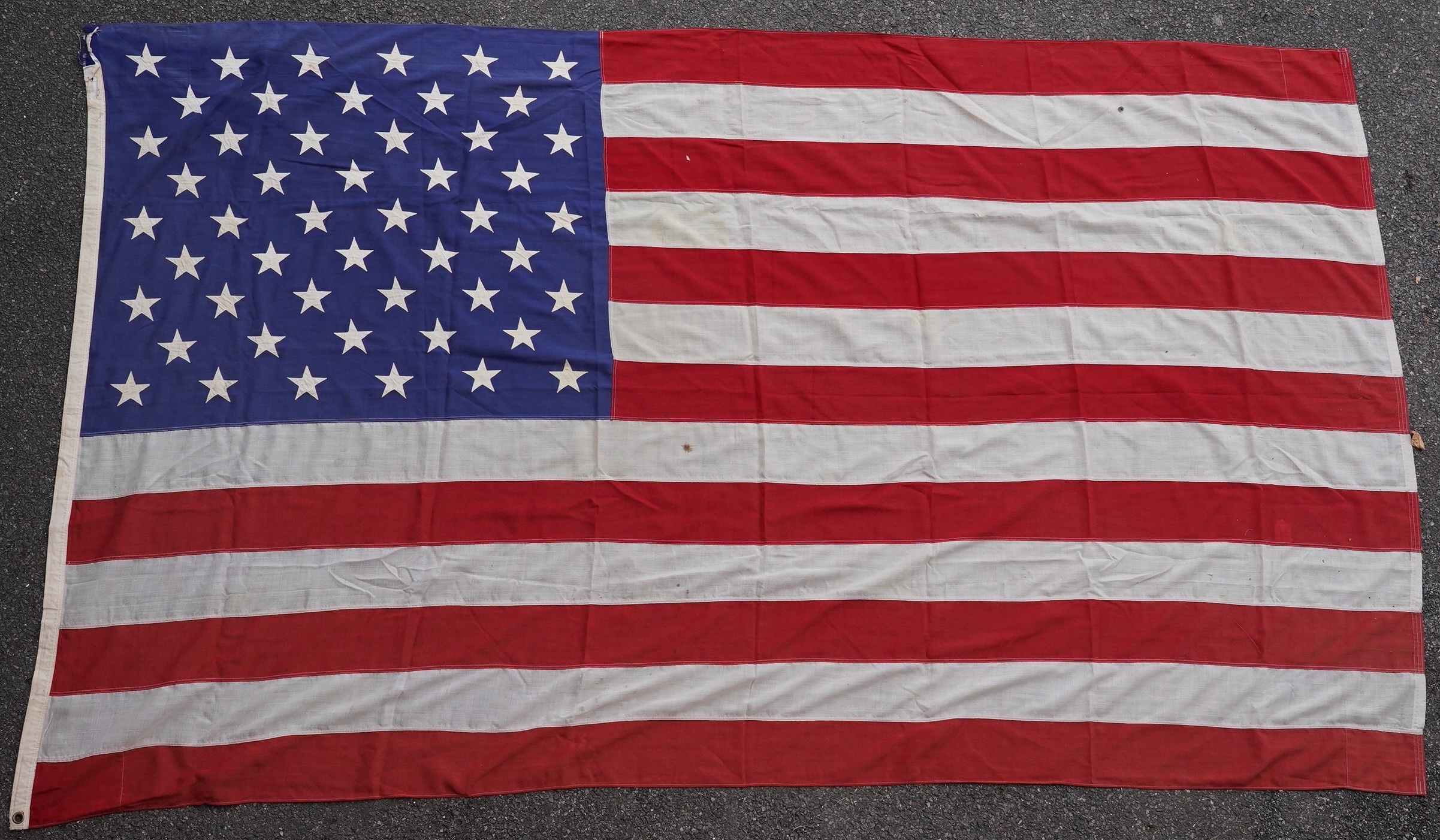 Four flags; two professionally made US Stars and Stripes, both on thick canvas with applied stars and joined stripes, one by the Valley Forge Flag Co., Pennsylvania, stamped “5 x 9.5 ft”, 146 x 288cm and 176 x 300cm, tog